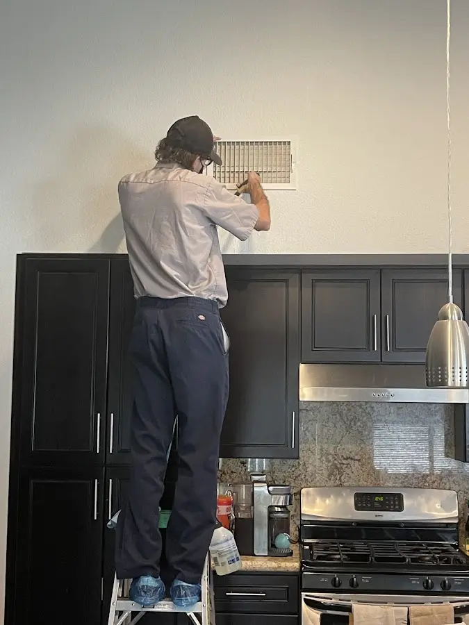 Technician inspecting an air vent during HVAC service in South Riding